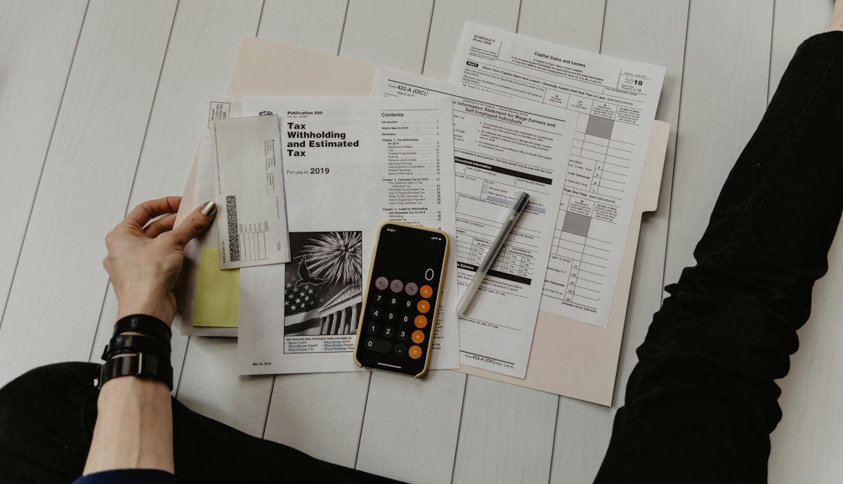 Formularios y documentos fiscales junto a una calculadora sobre un escritorio